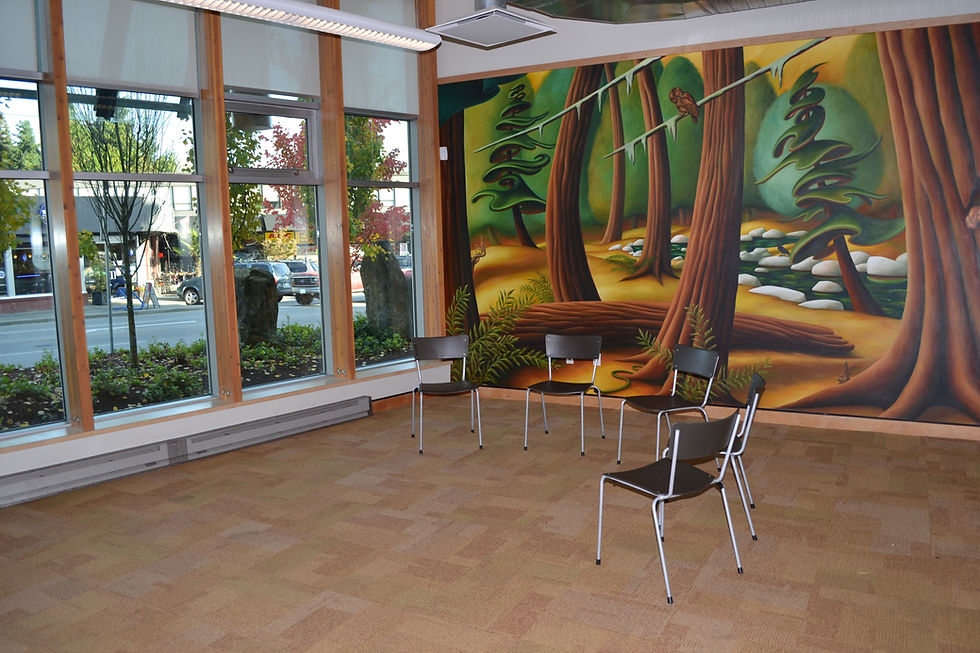 Picture of a meeting with five chairs in a semi-circlein front of a wall of windows. The back wall is a large mural of trees blowing in the wind.