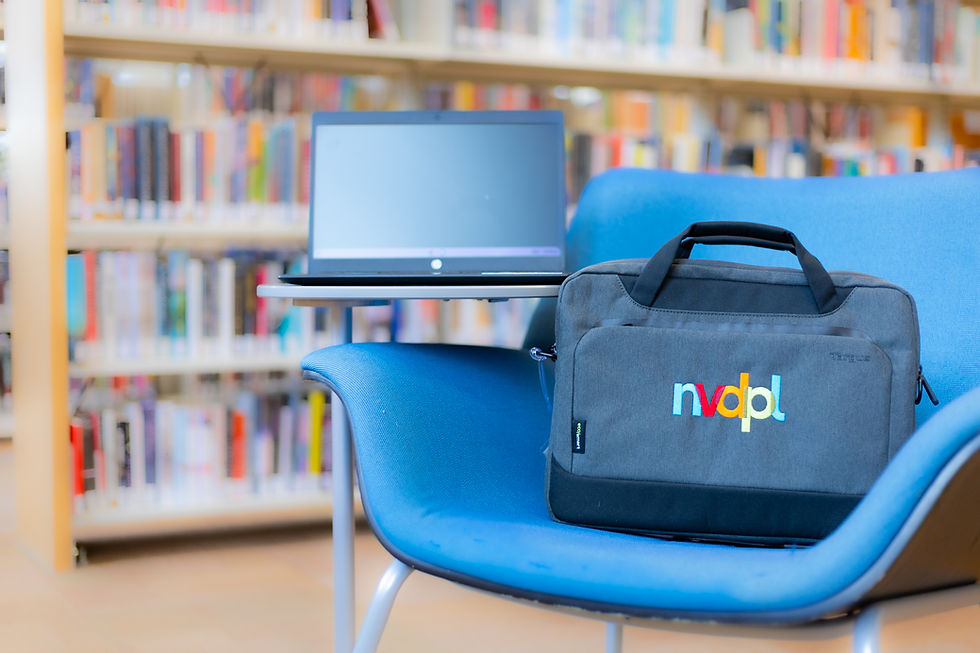 A laptop case sitting on a chair while an open laptop is resting on a table attached to the chair.