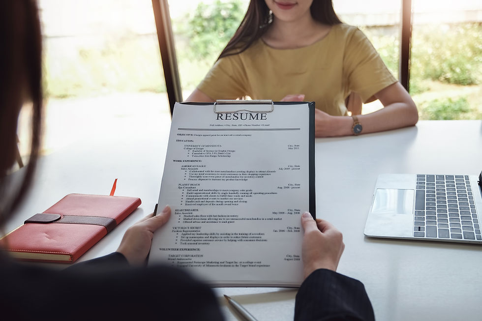 A stock photo of an interviewer and someone being interviewed. The interviewer is holding up a resume.