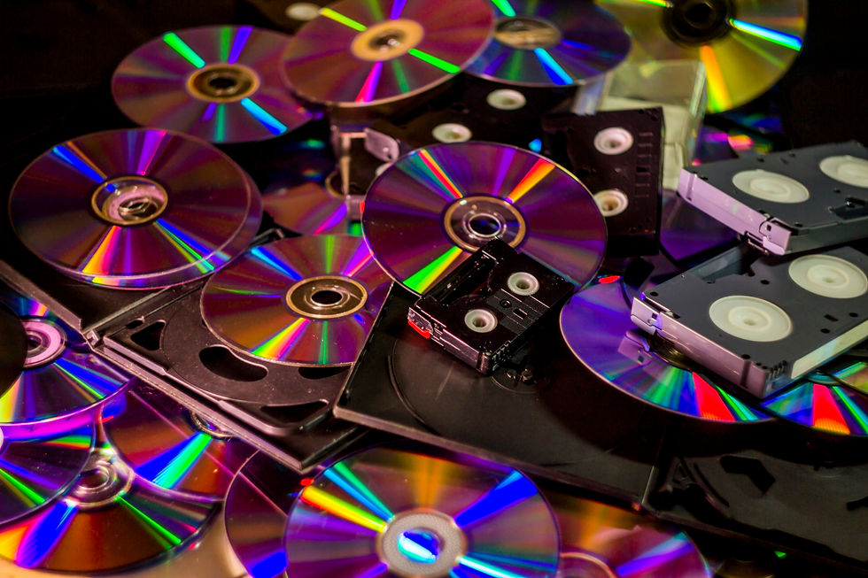 A pile of old media including optical discs, casette tapes, and VHS tapes.