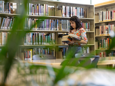 person looking at a book in front of other books